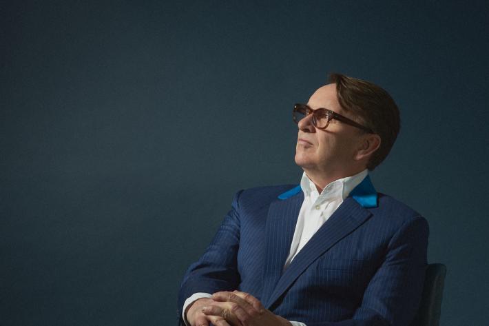 Portrait of Chris Difford in a suit and seated