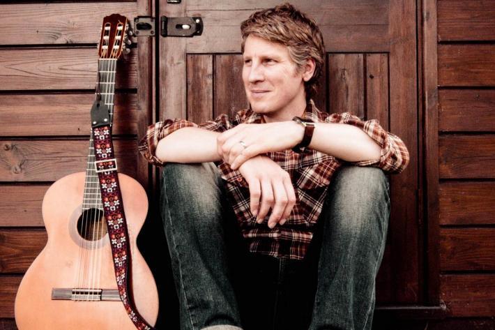 Scott Matthews sitting on a step with his guitar